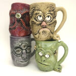 4 colored mugs with faces by artist Richard OKrogly