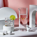 Clear pitcher and glass with colorful flowers by artist Tate Newfield