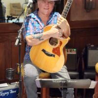 Don Cook Musician Don Cook sitting on stage holding guitar